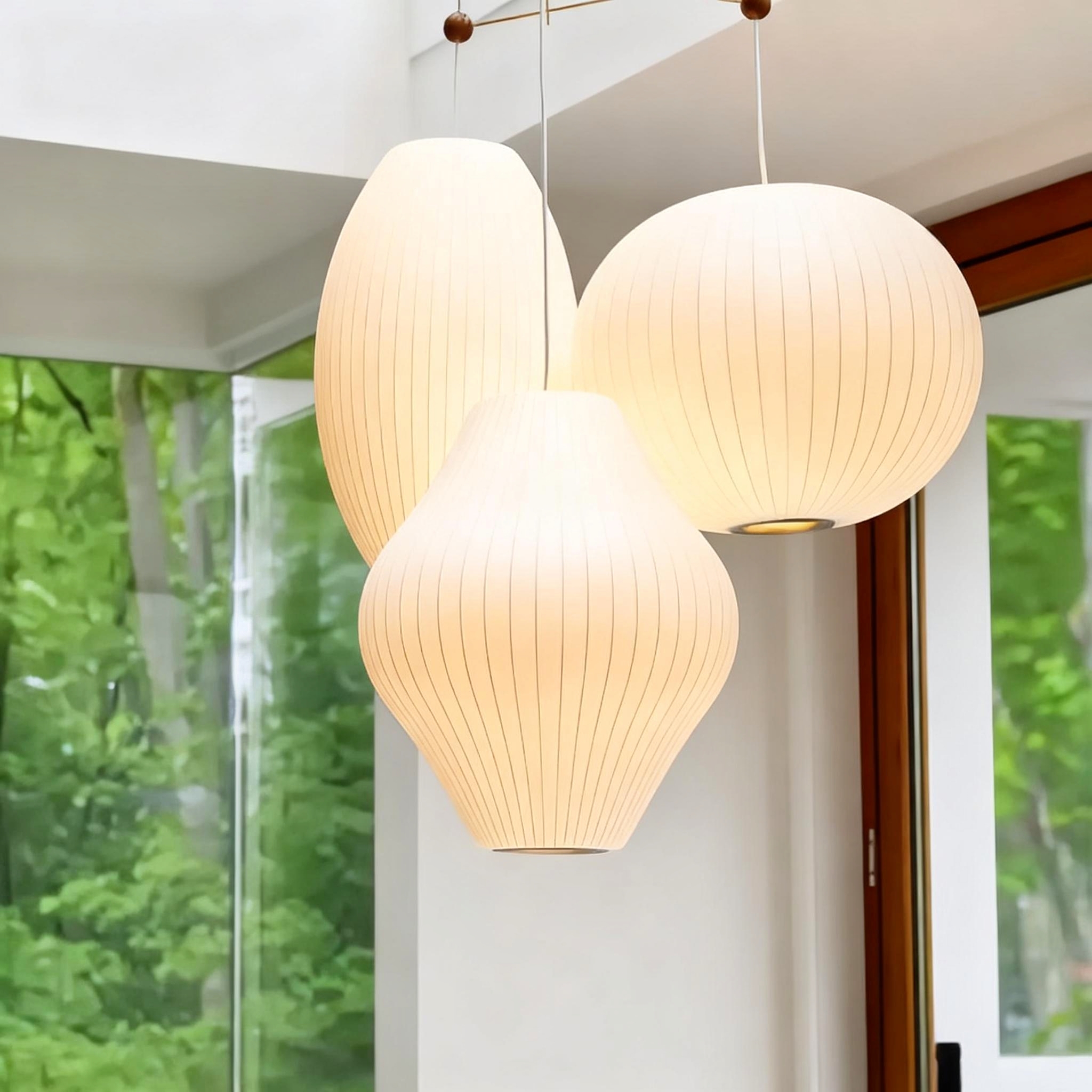  minimalist home. A cluster of three warm-toned, ribbed white paper origami pendant lamps hanging at staggered heights indoors.