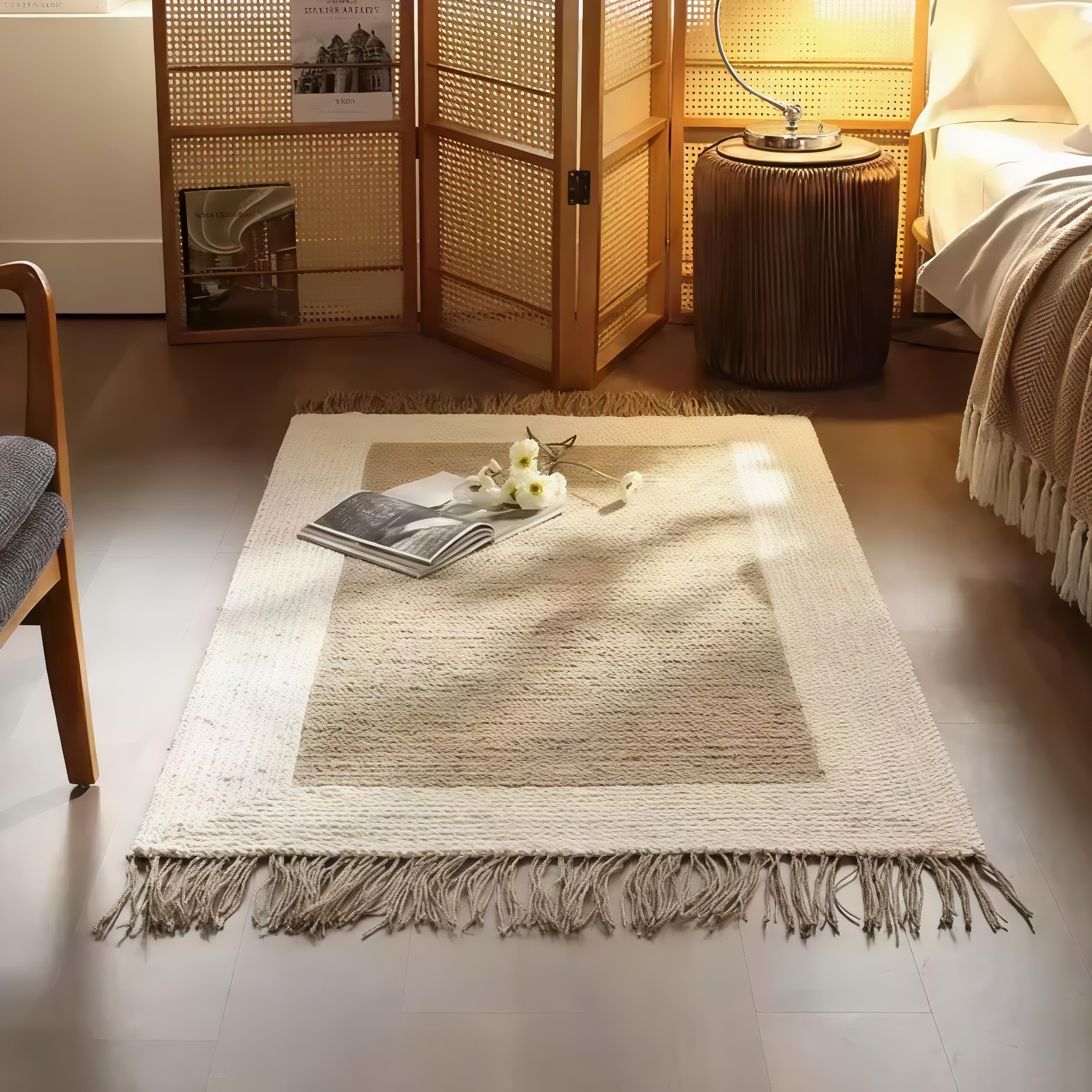 minimalist area rugs. A rectangular, textured cream and beige area rug with fringed edges on a dark floor, positioned near a woven rattan room divider and a small round side table.